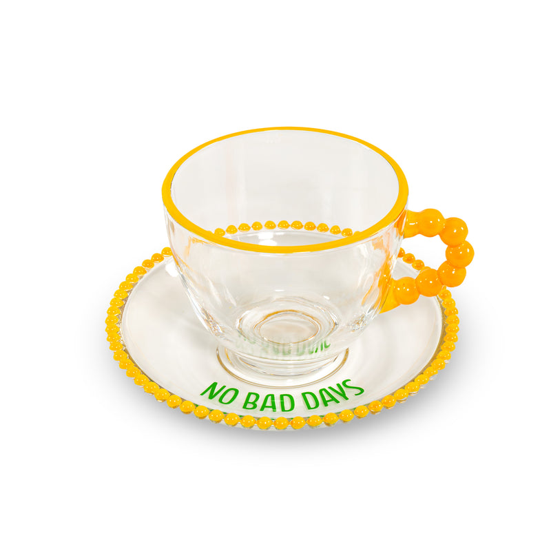 Lot de 2 tasses en verre WD LifeStyle de 230 ml avec soucoupes, décorées avec les inscriptions « Que de la bonne énergie » et « Pas de mauvais jours », jaune et vert.